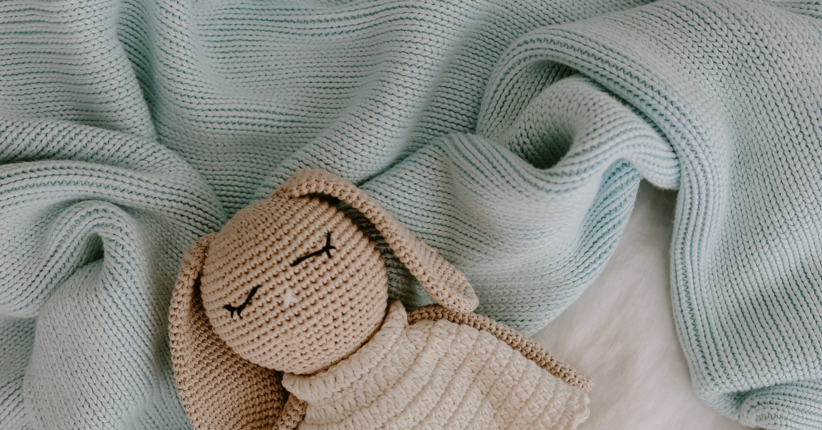 Soft natural bamboo weighted blanket on the bed with a crochet doll