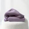 Woven Woven 3.0kg Jacaranda Purple kids bamboo weighted blanket folded on a cream boucle ottoman.
